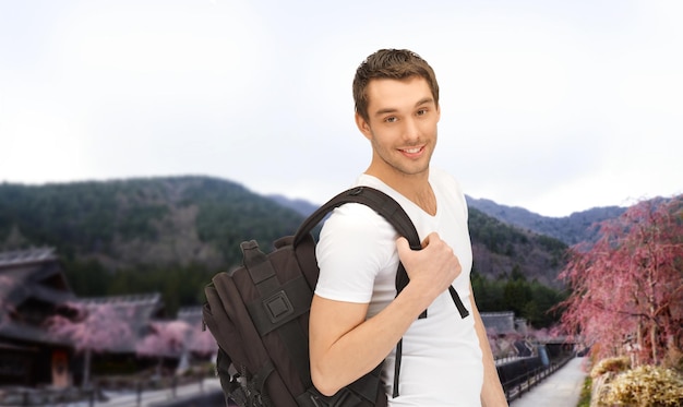 concepto de personas, viajes, turismo y educación - joven feliz con mochila y libro que viaja sobre el fondo del paisaje asiático