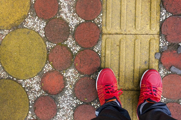 Concepto de pies con zapatos rojos en un fondo de suelo de ladrillos de colores con espacio para el texto