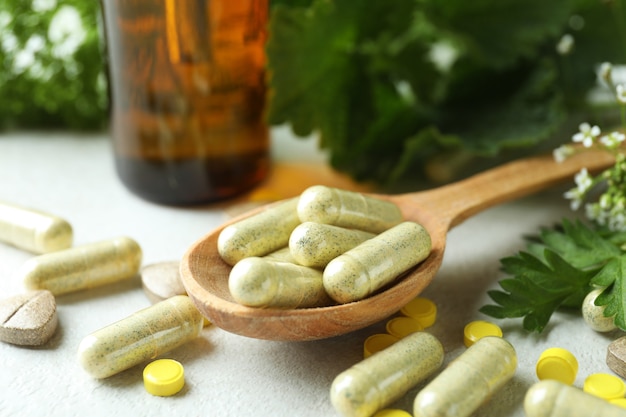 Concepto de píldoras de hierbas medicinales en la mesa con textura blanca, cerrar