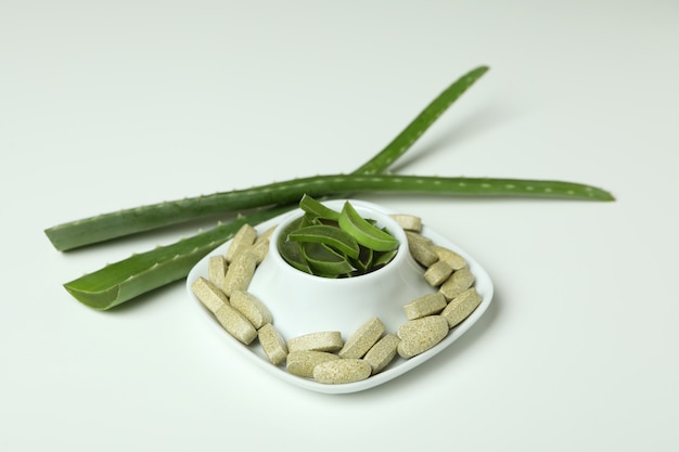 Concepto de píldoras de hierbas naturales con aloe sobre fondo blanco.