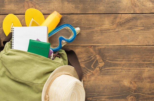 Foto concepto de planificación de viajes. mochila plana con cuaderno en blanco y accesorios de viajero en mesa de madera