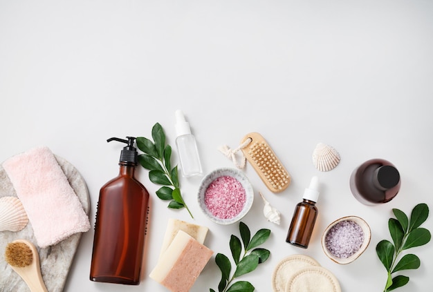 Foto concepto plano de cosméticos para el cuidado facial y corporal con sal marina jabón esponja cepillo loción conchas crema sobre fondo blanco vista superior y espacio de copia