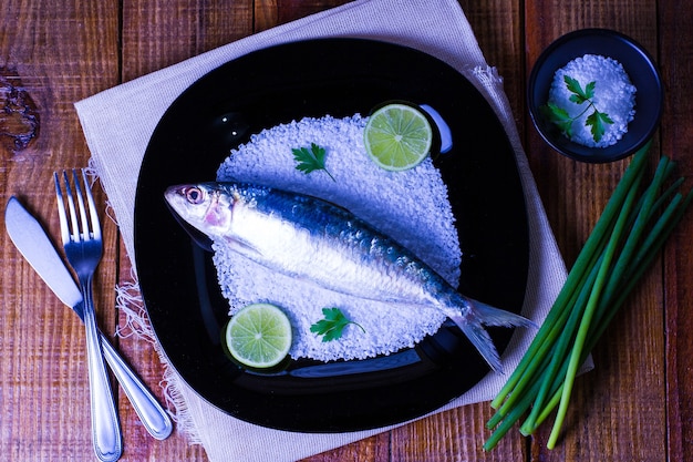 Concepto de plato con sardinas sobre sal gruesa en placa negra