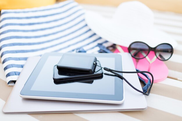 concepto de playa, vacaciones de verano y tecnología - cierre de tablet pc, smartphone, cámara y accesorios de verano en la playa