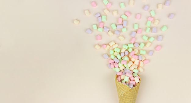 Concepto de postre dulce, malvavisco dulce y brillante en forma de helado en una taza de gofre en el medio.