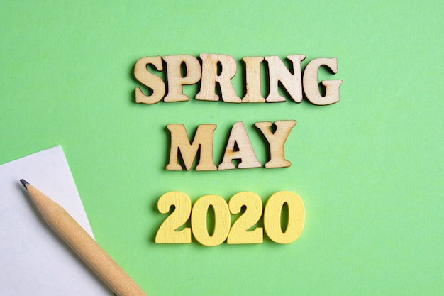 El concepto de primavera - mayo en el nuevo año. Números de madera 2020 con letras y hoja de papel con lápiz