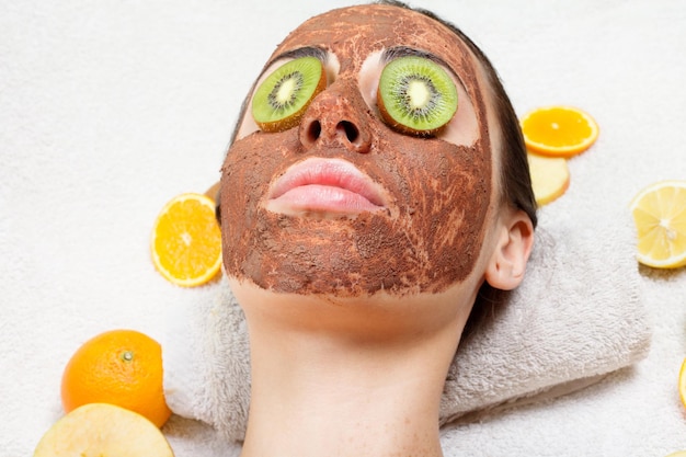 Foto concepto de primavera, salud, gente, juventud y belleza -máscaras faciales de frutas naturales caseras. fruta fresca. mujer de spa aplicando mascarilla limpiadora facial. tratamientos de belleza