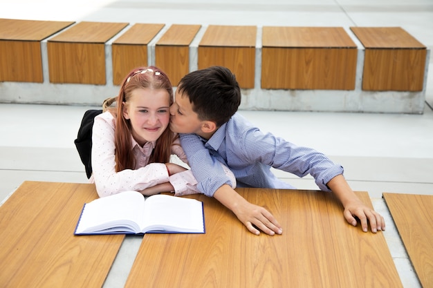 Concepto de primeros sentimientos, primer beso, amor escolar. niño besa a niña, adolescente está muy feliz y sorprendido, infancia, vida escolar, estilo de vida