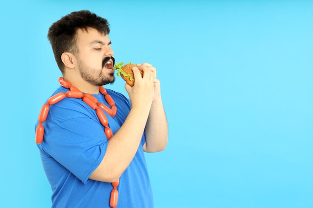 Concepto de problemas de peso joven gordo sobre fondo azul.