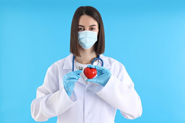 Foto concepto de profesión joven doctora sobre fondo azul.