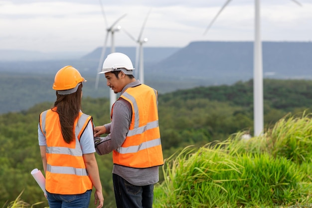 Foto concepto progresivo de ingenieros que trabajan en el parque eólico en la cima de la montaña