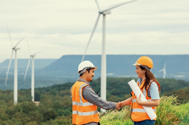 Concepto progresivo de ingenieros que trabajan en el parque eólico en la cima de la montaña