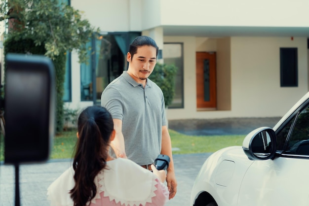 Concepto progresivo de padre e hija con coche EV y estación de carga doméstica