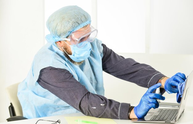 concepto de protección. concepto de trabajo remoto. hombre con uniforme médico. el hombre usa mascarilla respiratoria, guantes y gafas protectoras. mantente a salvo en casa. brote de pandemia de coronavirus. higiene en el encierro.