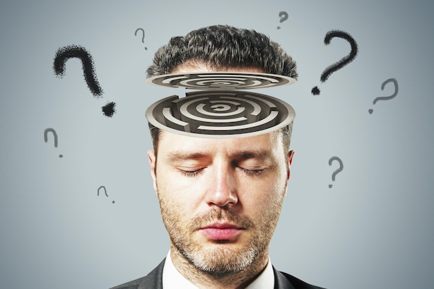 Concepto de psicología y conciencia humana con cabeza de hombre con laberinto y signos de interrogación sobre fondo gris