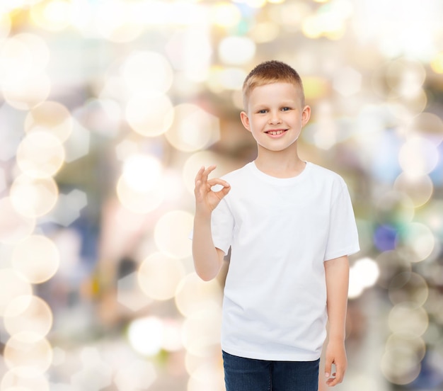 concepto de publicidad, fiesta, gente e infancia - niño pequeño sonriente con camiseta blanca en blanco haciendo un buen gesto durante las vacaciones