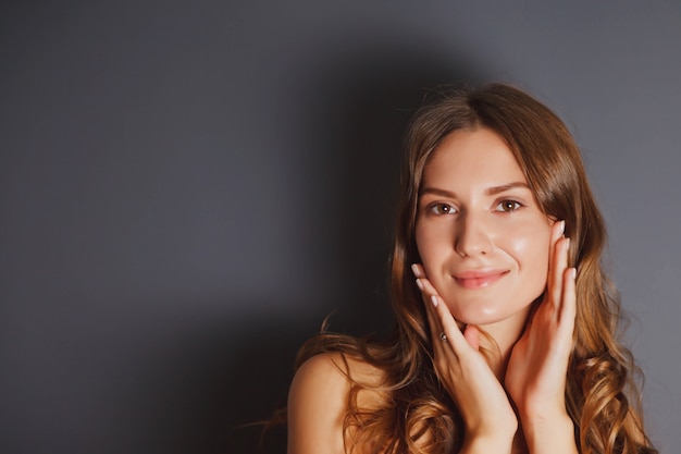 Concepto publicitario de sorpresa y miedo. Retrato de primer plano bastante joven asustada con las manos a la cara contra el fondo oscuro aislado. Cicatriz de emoción de actriz femenina. Copie el espacio para el sitio