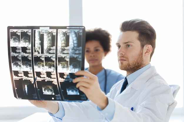 Foto concepto de radiología, cirugía, atención médica, personas y medicina - médico y enfermera mirando la imagen de rayos x de la columna vertebral en el hospital