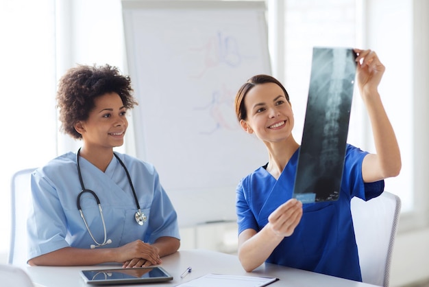 concepto de radiología, cirugía, personas y medicina - doctoras felices mirando y discutiendo la imagen de rayos X en el hospital