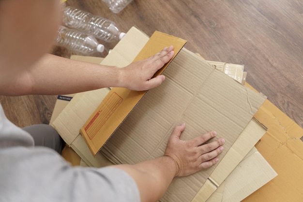 Concepto de reciclaje ecológico de cero residuos en el hogar Hombre que utiliza cajas de papel reciclado Apilamiento de cajas de cartón marrón envases ecológicos hechos de materias primas reciclables