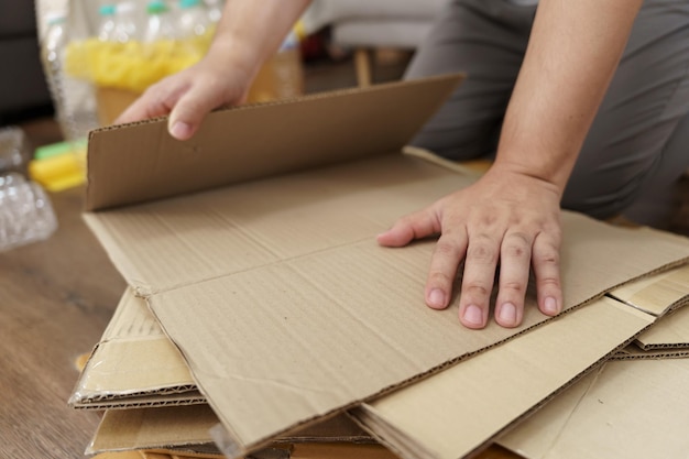 Concepto de reciclaje ecológico de cero residuos en el hogar Hombre que utiliza cajas de papel reciclado Apilamiento de cajas de cartón marrón envases ecológicos hechos de materias primas reciclables