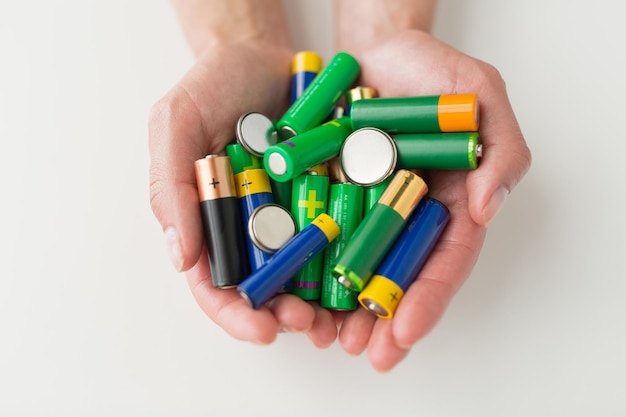 concepto de reciclaje, energía, energía, medio ambiente y ecología - cierre de manos que sostienen pilas alcalinas