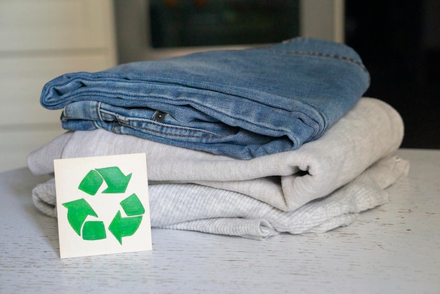 Concepto de reciclaje de prendas de vestir. Hay una pila de ropa en la mesa de reciclaje. Recogida de ropa para reciclaje