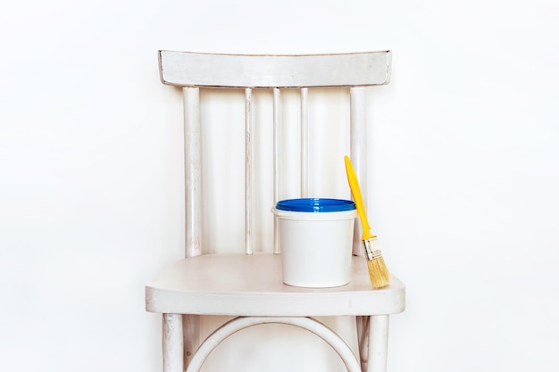 Concepto de reciclaje. Repintar una silla vieja. Silla, pintura y cepillo de madera blancos viejos.