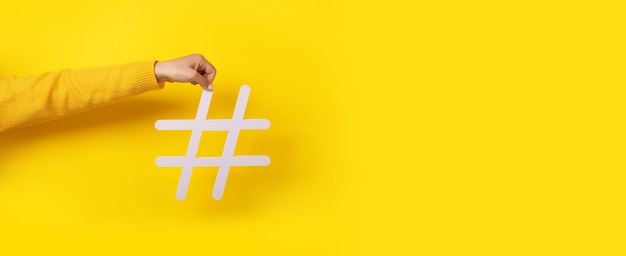 Concepto de redes sociales, mano sosteniendo gran cartel hashtag blanco