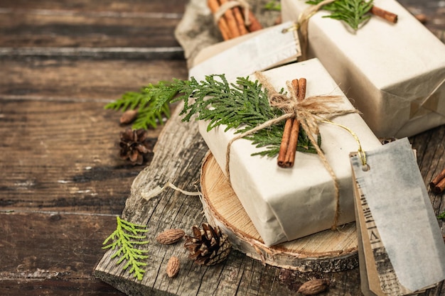 Concepto de regalo sin desperdicio. Embalaje ecológico de Navidad o Año Nuevo. Cajas festivas en papel artesanal con diferentes decoraciones orgánicas. Fondo de madera vintage, espacio de copia