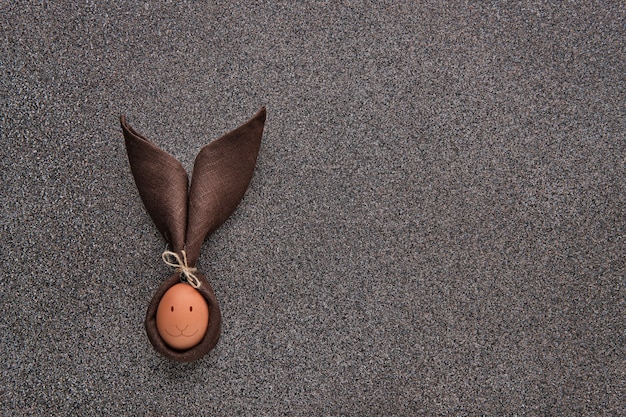 Concepto de regalo de Pascua: huevo envuelto en forma de conejito en piedra oscura