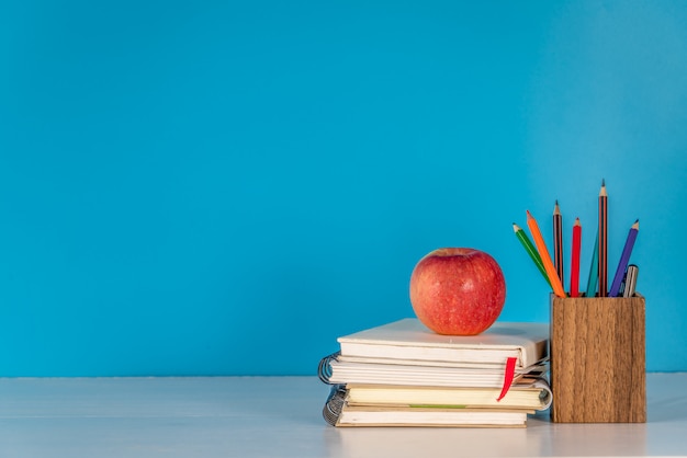 Concepto de regreso a la escuela Apple y útiles escolares en mesa blanca