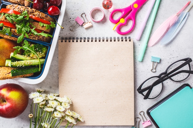 Concepto de regreso a la escuela con fiambrera con sandwich, frutas, bocadillos, cuaderno, lápices y artículos escolares