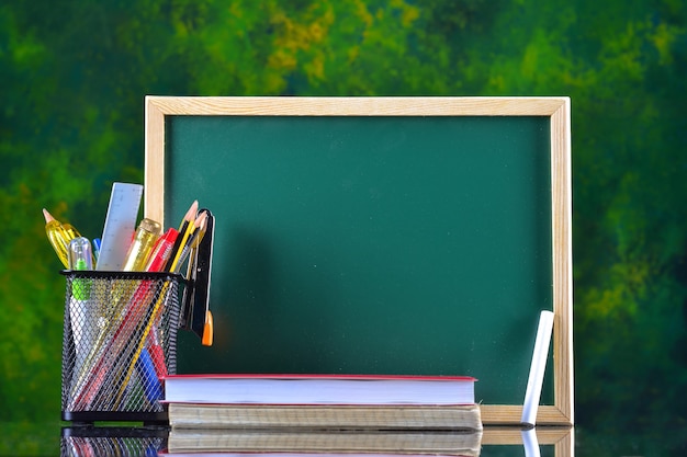 Concepto de regreso a la escuela con papelería en la mesa frente a la pizarra