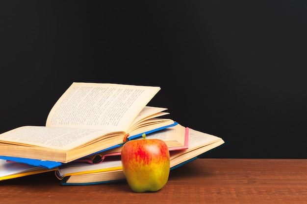 Concepto de regreso a la escuela. Pizarra con libros y manzana en escritorio de madera