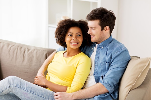 Concepto de relaciones, amor y personas: feliz pareja internacional sonriente abrazándose en casa