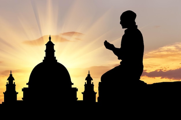 El concepto de religión es el Islam. Silueta de hombre rezando al atardecer y la mezquita