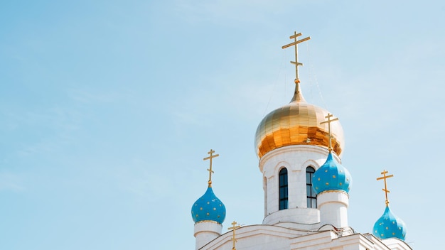 Concepto de religión y fe Iglesia cristiana con cúpulas doradas y azules y cruces contra el cielo azul claro en un día soleado al aire libre copia espacio