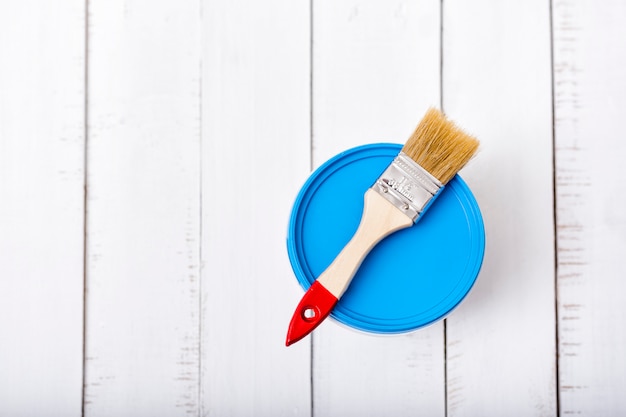 Concepto de renovación de la casa. Cepillo y un cubo de pintura en tablones de madera en mal estado blanco.