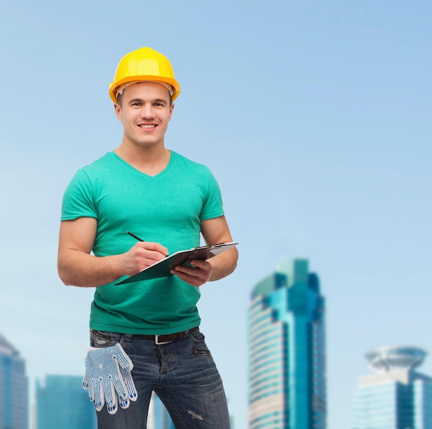 concepto de reparación, construcción y mantenimiento - hombre sonriente en casco con portapapeles