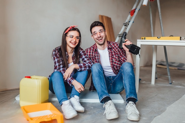 Concepto de reparación, construcción, renovación y hogar. Pareja haciendo reparaciones en casa, vistiendo ropa protectora bien equipada con caras y ropa desordenada