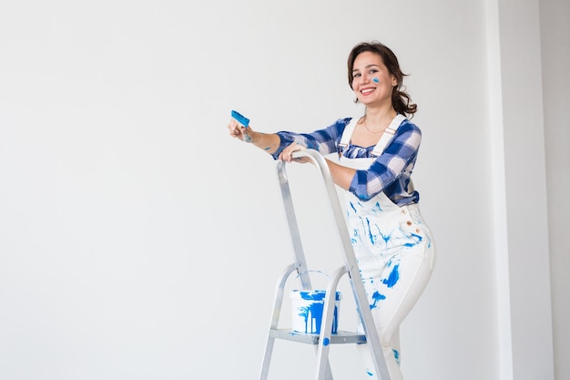 Foto concepto de reparación, renovación y personas: pared de pintura de mujer joven feliz en casa con espacio de copia