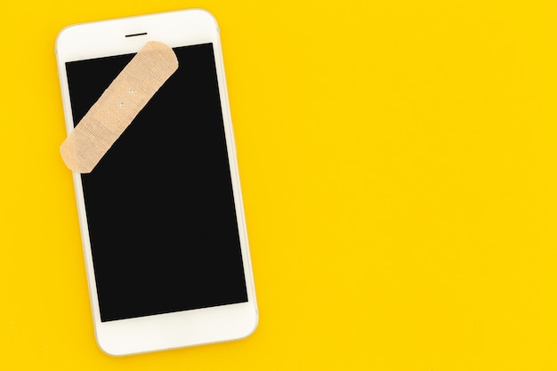 Concepto de reparación de teléfonos inteligentes. Teléfono con una pantalla en blanco en la vista superior de fondo amarillo