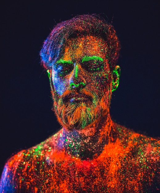 Concepto. Retrato de un hombre barbudo. El hombre está pintado con polvo ultravioleta.