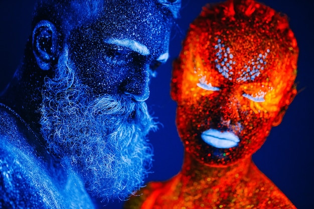 Concepto. Retrato de un hombre y una mujer con barba pintados en polvo ultravioleta.