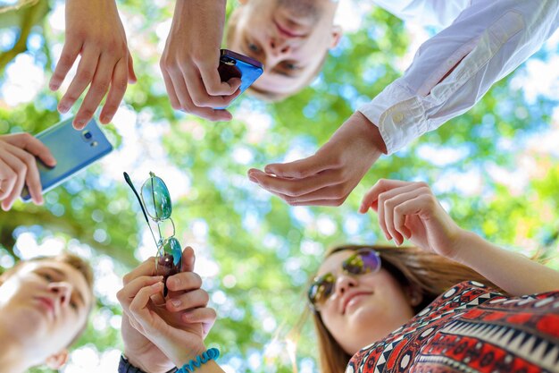 Concepto de reunión de intercambio de ideas de trabajo en equipo. Personas de pie en círculo y usando teléfonos inteligentes, primer plano. Vista hacia abajo