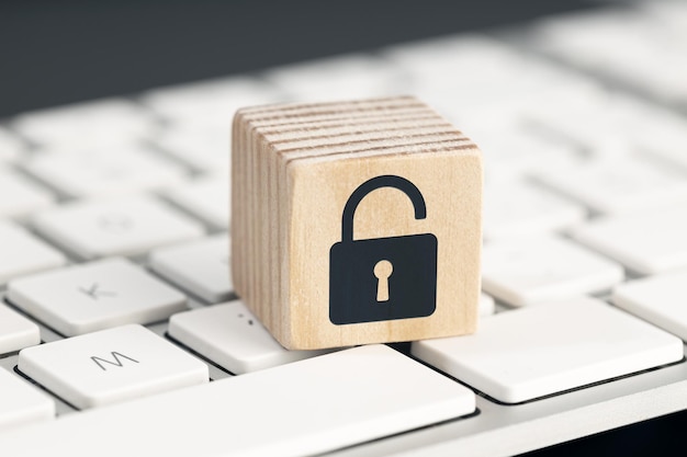 Foto concepto de riesgo de seguridad informática icono de candado abierto en cubo de madera en el teclado de la computadora
