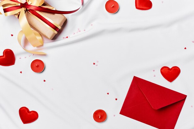 Foto concepto romántico fondo del día de san valentín sobre rojo caja de regalo y corazones en hoja de seda blanca