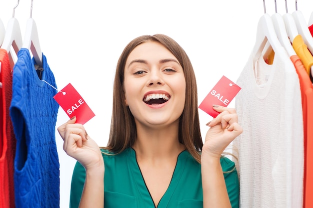 concepto de ropa, moda, venta, compras y personas - mujer feliz mostrando etiquetas en la ropa en el armario de casa o en la tienda