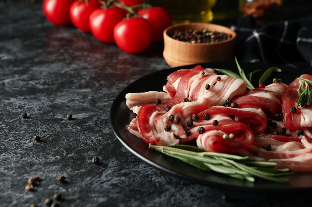 Concepto de sabroso aperitivo con plato de tocino sobre fondo negro ahumado